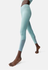 Leggings azzurri chiari realizzati in un tessuto morbido e elasticizzato. Presentano un vita media e un pannello grigio a contrasto nella parte inferiore della gamba.