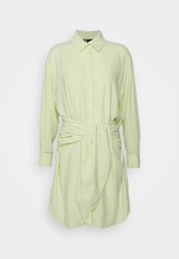 Robe chemise vert pâle à manches longues avec col, boutonnée devant, et ceinture en tissu nouée à la taille.