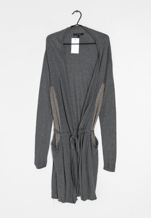 Grauer Langarm-Cardigan mit offener Vorderseite, Kordelzug in der Taille, karierten Seitenteilen und Fronttaschen, an einem schwarzen Kleiderbügel hängend.