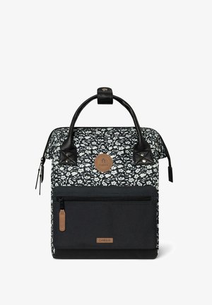 Schwarz-weißer Rucksack mit floralen Mustern, zwei schwarzen Griffen, einer Fronttasche und einem braunen Logo-Patch. Aus strapazierfähigem Stoff gefertigt.