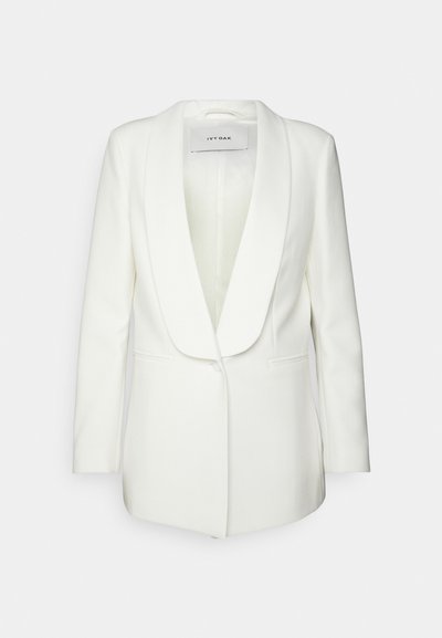 Hvid blazer med sjalslapel, enkelt knap lukning, to frontlommer og en glat stofstruktur. Indvendig foring synlig ved kraven.