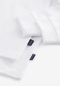 Weißes langärmliges T-Shirt mit weicher Textur; verfügt über zwei Etiketten mit "BAKER"-Logo am Saum und an den Ärmelbündchen.