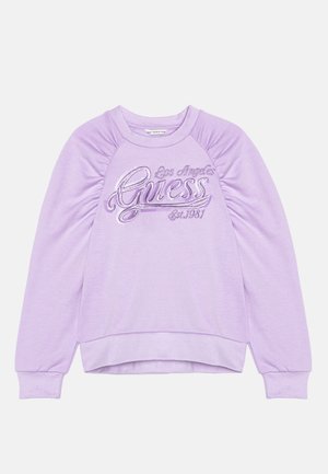 Sweat-shirt à manches longues lavande avec épaules froncées et "Los Angeles Guess Est. 1981" brodé en cursive sur le devant.