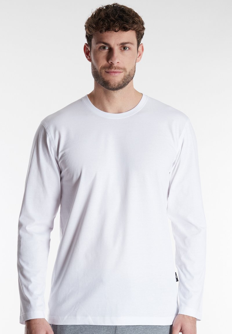 White long-sleeve t-shirt made of soft fabric with a crew neckline and relaxed fit. Displays minimalistic design, no patterns or embellishments.