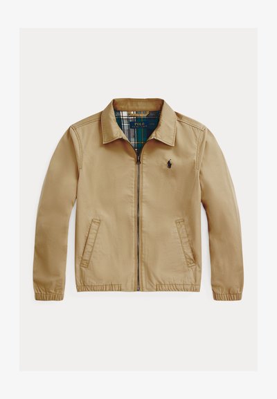 Casaco leve bege com fecho éclair à frente, colarinho espalhado e dois bolsos laterais. Apresenta um forro xadrez e um logótipo bordado no peito.