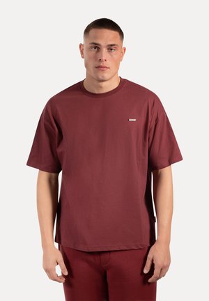Maroon katoenen t-shirt met een ronde hals, korte mouwen en een klein merklabel op de linkerborst, ontworpen met een ontspannen pasvorm.