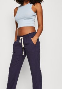 Top court bleu clair avec texture côtelée associé à un pantalon marine foncé avec ceinture élastique et cordon de serrage, deux poches latérales.