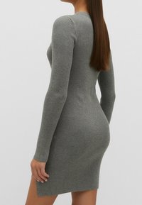 Szara dzianinowa sukienka o prążkowanej fakturze, z długimi rękawami, dopasowanym kroju i długości do kolan. Posiada detale teksturalne oraz boczne rozcięcia.