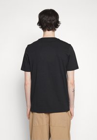 Zwart t-shirt met korte mouwen van katoen met een ronde halslijn. Eenvoudig ontwerp, relaxte pasvorm, geen zichtbare branding of patronen.