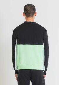 Sudadera color bloque en negro y verde menta con cuello redondo y mangas largas. Fabricada con un tejido suave y con puños y dobladillo acanalados.