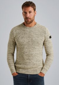 Pull beige texturé avec un col rond et des poignets c�ôtelés. Présente un motif de formes en losange entrelacées et un petit patch logo noir.