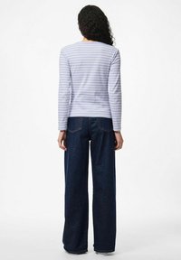 Blusa de manga larga de rayas azul claro en una tela suave, combinada con pantalones de pierna ancha de mezclilla oscura de cintura alta que presentan un diseño clásico de cinco bolsillos.