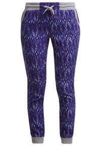 Lila joggers med ett geometriskt mönster och ljusblå detaljer, grå midja och muddar. Tillverkade av mjukt material med fickor.