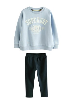 Ljusblå sweatshirt med "SUPERDRY"-logotyp i vitt, kombinerad med svarta leggings. Mjukt tyg, lös passform, ribbad mudd och midja.