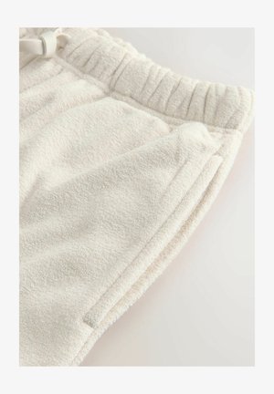 Cremefarbene Fleece-Sweatpants mit elastischem Bund und sichtbarem Seitentasche auf einem schlichten hellen Hintergrund.