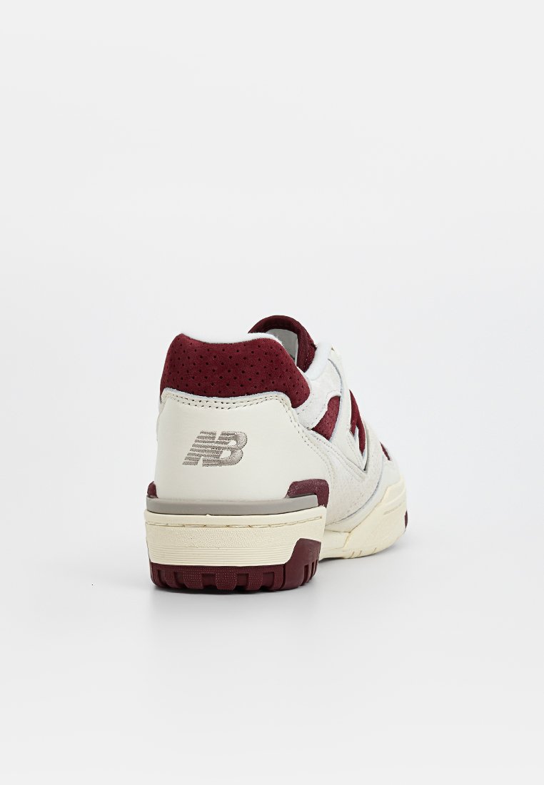 Sneaker con una parte superiore in pelle bianca caratterizzata da accenti bordeaux, sezioni perforate e una suola testurizzata. Logo argento sulla parte posteriore, design a profilo basso.
