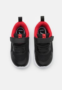 Chaussures de sport noires avec tige en mesh, doublure intérieure rouge et semelles blanches. Possède des lacets et une sangle Velcro pour un maintien sécurisé.