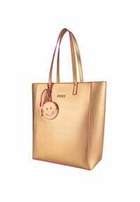 Gouden handtas met een gladde metallic textuur, rozenkleurige accenten op de randen en banden, met een ronde bedel met een glimlachend gezicht.