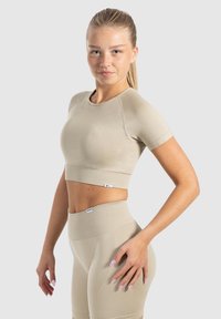 Beige crop top met korte mouwen en een brede ribbelrand, gedragen met bijpassende high-waisted shorts; gladde textuur, aansluitend ontwerp.