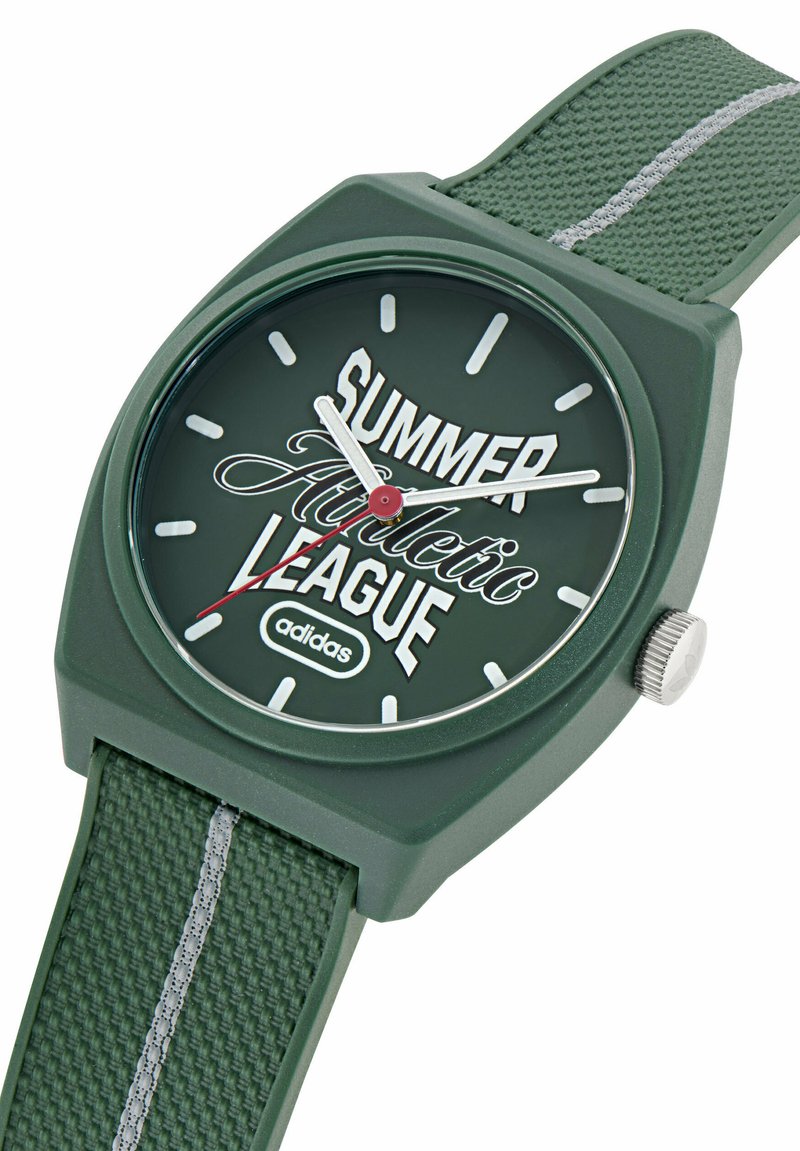 Reloj de pulsera Adidas verde con correa texturizada y marcadores de hora blancos, mostrando "Liga Atlética de Verano" en la esfera, indicando las 10:09:39.