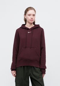 Bordo kapučen pulover iz mehkega materiala, z sprednjo žepno, nastavljivimi vrvicami in belim Nike logotipom na prsih.