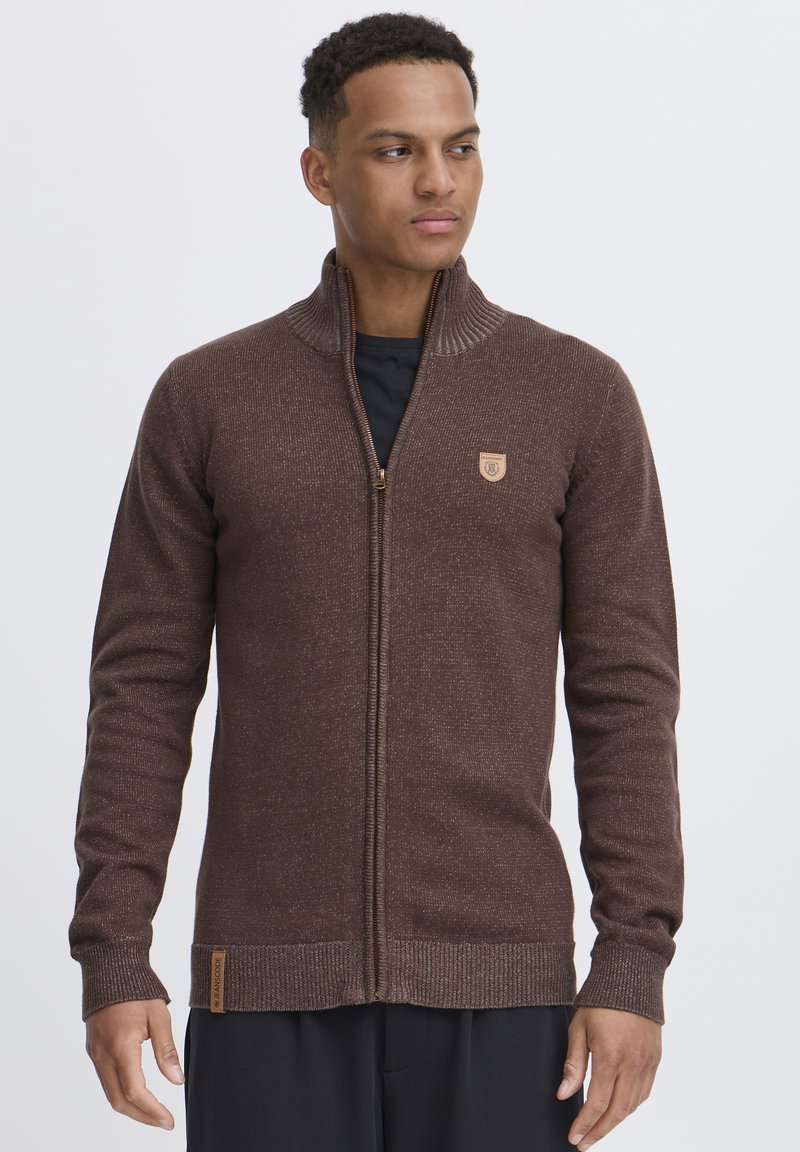 Brauner Reißverschluss-Strickcardigan mit strukturiertem Strick, gerippten Bündchen und Kragen. Mit einem kleinen Emblem auf der Brust und einem Stoffetikett am Saum.