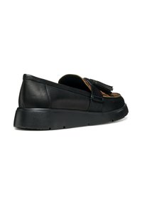 Scarpa slip-on in pelle nera con dettaglio a nappina, suola piatta in gomma, interno testurizzato e cuciture a contrasto lungo i bordi.