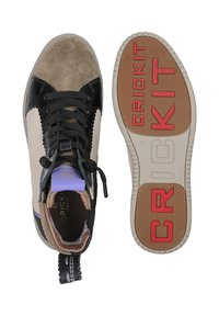 Wysokie trampki z czarnej lakierowanej skóry, beżowego zamszu oraz fioletowych akcentów. Posiadają gumową podeszwę z czerwoną grafiką "CRICKIT" oraz czarnymi sznurówkami.
