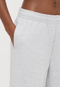 Γκρι φόρμα με απαλό, υφασμάτινο υλικό με υφή, που διαθέτει πλαϊνές τσέπες και ελαστική μέση για άνετη εφαρμογή.