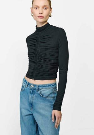 Czarna bluzka z długim rękawem i zamkiem z przodu, z marszczonym wzorem, w połączeniu z jasnoniebieskimi dżinsami z wysokim stanem. Prosty design, dopasowany krój.