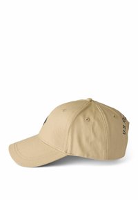 Cotton baseball cap in tan with a curved visor, featuring a black logo embroidery and ventilation eyelets on the sides.