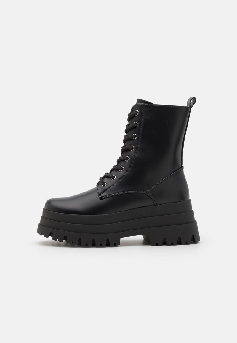 Bottines en cuir noir avec une semelle plateforme épaisse, design à lacets et œillets en métal. Équipées d'une languette à l'arrière pour un enfilage facile.