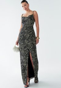 Maxi dress with a black background and abstract white leaf pattern, featuring a fitted bodice, spaghetti straps, and a thigh-high slit.