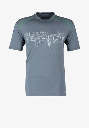 T-shirt de sport gris avec des accents verts et un motif textuel, associé à des leggings noirs avec une texture hexagonale. Baskets noires.