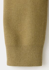 Gros plan d'une manche tricotée kaki avec un poignet côtelé en tissu doux et texturé.