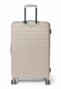 Valise rigide beige clair avec des rainures horizontales, une poignée rétractable et quatre roues pour la mobilité. Texture lisse.