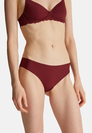 Bordowy stanik z koronkowym wykończeniem oraz dopasowane bezszwowe bikini. Miękka tkanina, gładka faktura i klasyczny krój z minimalnym zapięciem po bokach.