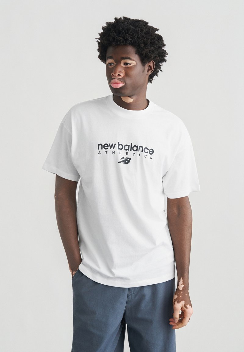 Λευκό βαμβακερό t-shirt με την επιγραφή «new balance ATHLETICS» σε έντονα μαύρα γράμματα, με στρογγυλή λαιμόκοψη και κοντά μανίκια. Διακριτική, casual εφαρμογή.