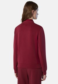 Roter Sweatshirt mit hohem Kragen, langen Ärmeln und strukturiertem Stoff. Enthält ein Logodetail am Hals und seitliche Akzente.