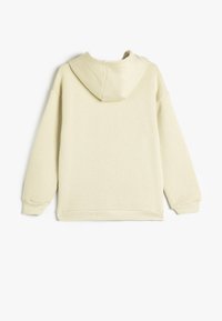 Sudadera con capucha color crema y corte relajado. Presenta una tela texturizada, puños y dobladillo de canalé, y un diseño suave y minimalista.