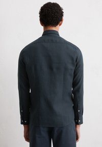 Donkerblauwe lange mouwen shirt van lichtgewicht stof, met een standaard kraag, knoopmanchetten en een gladde textuur, gezien vanaf de achterkant.