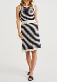 Stickad klänning med horisontella ränder i marinblått och kräm, ärmlös design, ribbad halsringning och midja samt en utsvängd nederkant med volang.