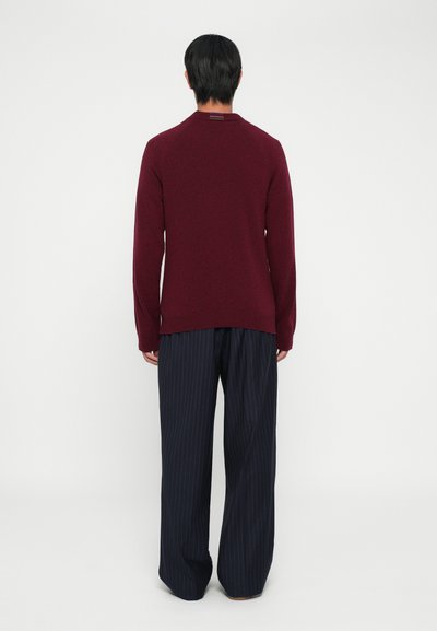 Maglione bordeaux a maniche lunghe con scollo rotondo, realizzato in materiale lavorato a maglia, abbinato a pantaloni a gamba larga a strisce blu navy. Design semplice e pulito.