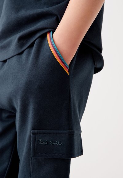 Námornícke tepláky s farebnými pruhmi na vreckách a vyšitou nášivkou s nápisom "Paul Smith." Z bavlny, voľný strih.