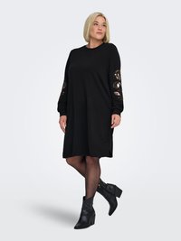 Must kleit pikkade varrukatega, millel on lilleline tikand varrukatel. Kangas on pehme ja lõdva lõikega. Kandmiseks koos mustade pahkluu saabastega.