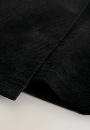 Schwarzer Cord-Stoff mit einer weichen, strukturierten Oberfläche, der sichtbare Rippungen und ordentlich gesäumte Kanten aufweist.