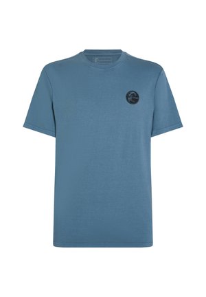 T-shirt en coton bleu avec un col rond, des manches courtes et un logo noir circulaire sur la poitrine gauche. Texture lisse et design à coupe décontractée.