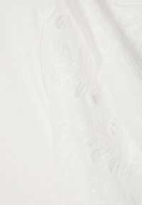 Weißer bestickter Stoff mit floralen Mustern und strukturierten Details. Die Stickerei ist dezent und fügt sich harmonisch in das Grundmaterial ein.