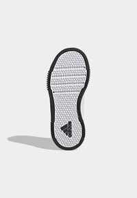 Valkoisessa tennaripohjassa on kuusikulmainen kuvio, mustat kumiset reunat ja Adidas-logo. Pinnassa on tekstuuri pitoon ja vakauteen.