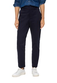 Námořnické modré kalhoty vyrobené z měkké látky s rovnými nohavicemi, s knoflíkovým zapínáním a bočními kapsami, doplněné o bílé tenisky.